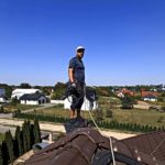 Łukasz Podlewski w trakcie instalacji anteny na dachu w domu jednorodzinnym.