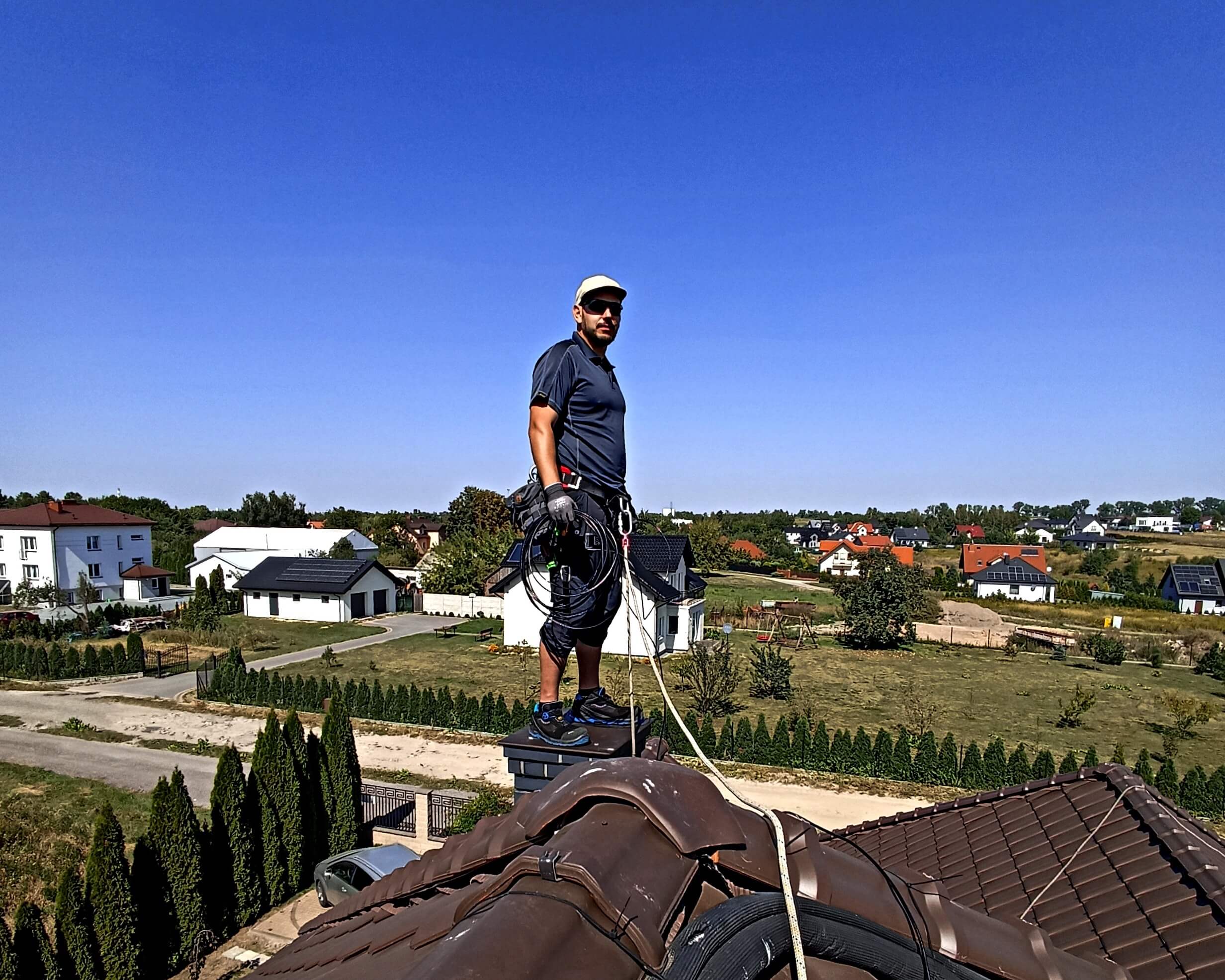 Łukasz Podlewski w trakcie instalacji anteny na dachu w domu jednorodzinnym.